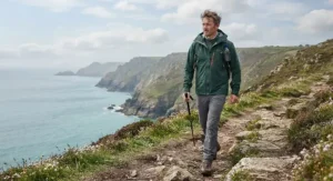 A person wearing a breathable mens hardshell jacket on a coastal path walk in Britain
