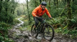 Mountain biker enjoying a rainy trail ride wearing the best cycling rain jacket