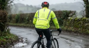 Rear view of a cyclist in a hi-vis cycling rain jacket featuring a large zipped pocket and high-visibility striping