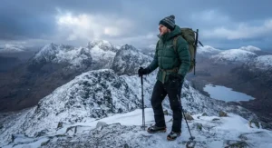 Hiker in a thermal insulated men's walking jacket standing on a snowy mountain ridge in Scotland