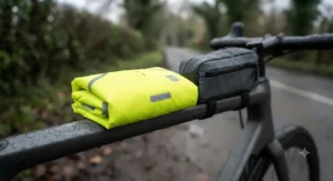Ultra-lightweight and packable hi-vis cycling rain jacket folded neatly next to a bike frame bag