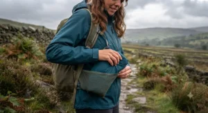 A woman packing her compact, foldable rain jacket into the side pocket of her daypack