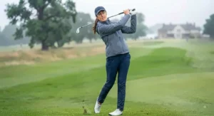 High-performance women's golf rain jacket showing a golfer completing a follow-through swing.