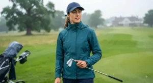 A golfer wearing a packable, lightweight women's golf waterproof mac on a drizzly day at a UK course.