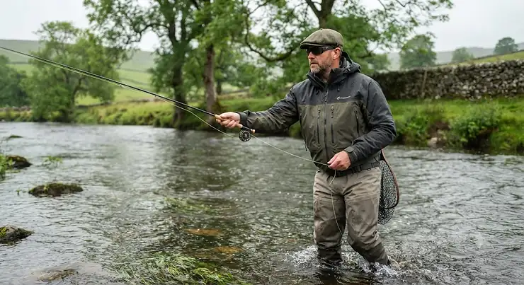 Man wearing a waterproof breathable fishing jacket while fly fishing on a British river