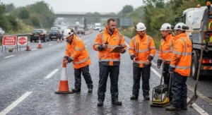 A group of road maintenance workers wearing hi-vis waterproof jackets standing on a UK road.