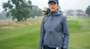 A golfer protected by a windproof and waterproof women's golf jacket in challenging British weather.