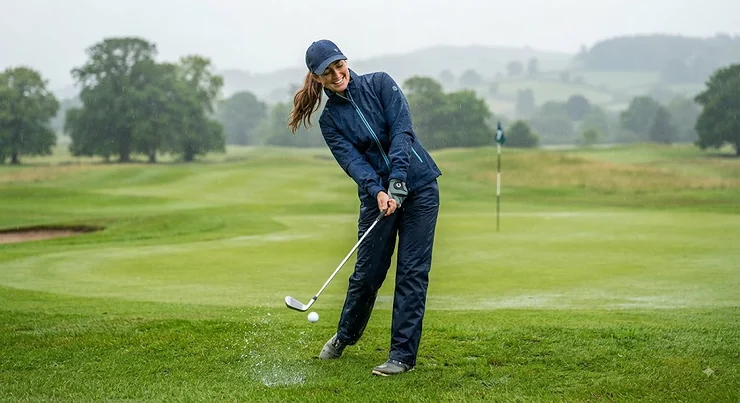 A woman wearing a stylish, lightweight waterproof golf jacket while playing on a green in light rain. womens golf rain jacket