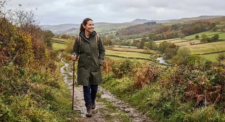 Woman wearing a khaki long waterproof coat while walking in the countryside