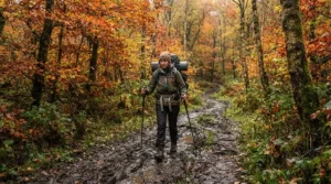 A backpacker wearing men's rain trousers UK style on a soggy autumn trail in the Peak District.