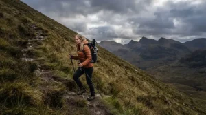 Hiker wearing a black waterproof padded coat on a rugged hillside trail